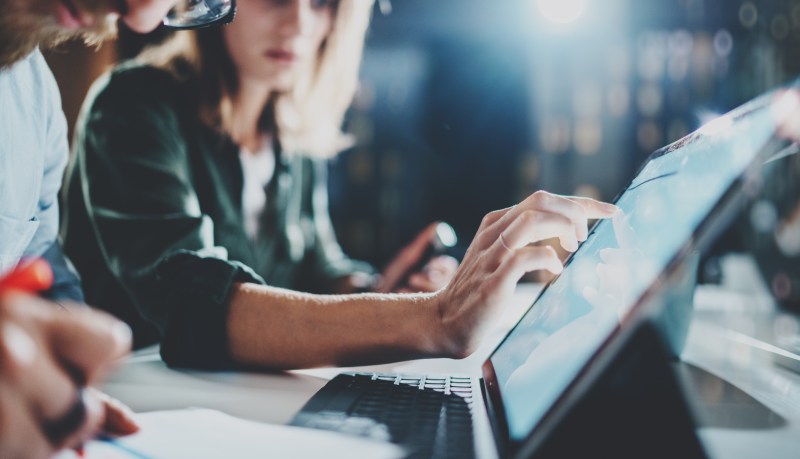 Woman pointing on digital tablet screen at night office .Horizontal.Blurred background.Flares. Woman pointing on digital tablet screen at night office .Horizontal.Blurred background.Flares