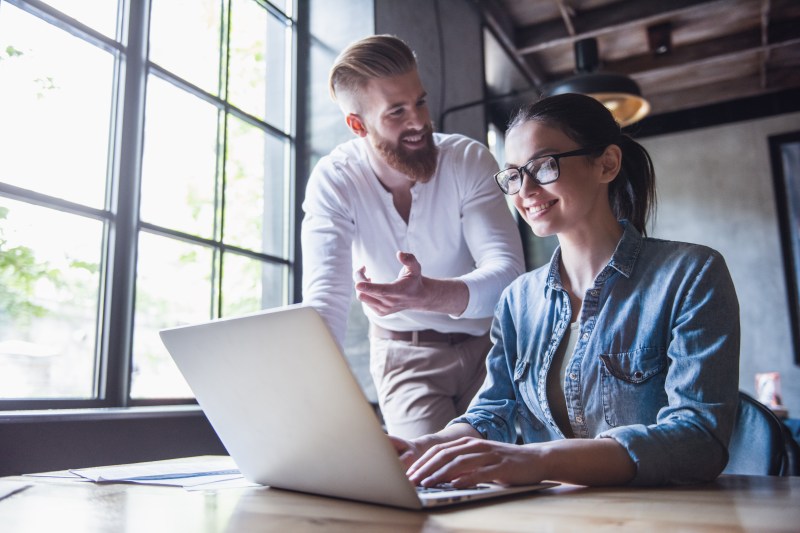 Young successful men and women use a laptop while working in the office
